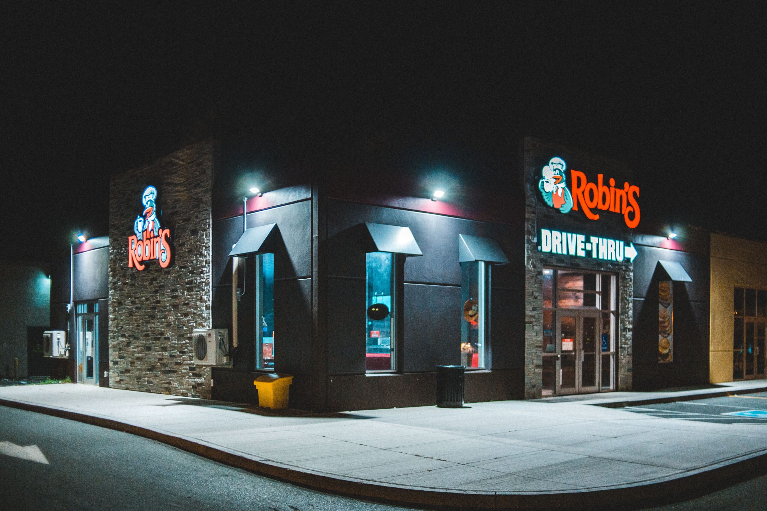 Facade of modern cafe with glowing signboards on street in city at night time